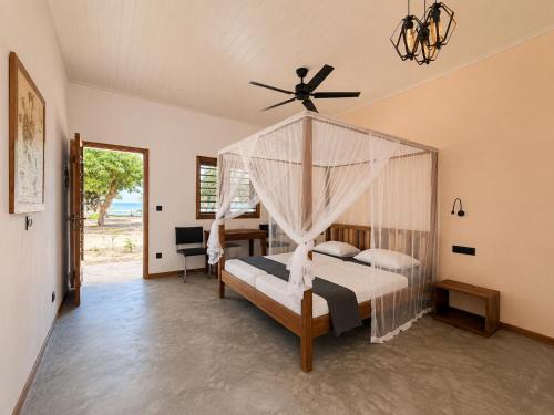a bedroom with a canopy bed with a ceiling fan at Maison le Rêve in Nosy Be