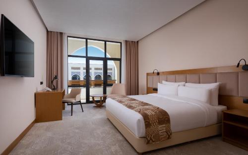 a bedroom with a bed and a desk and a television at Farovon Khiva Hotel in Khiva