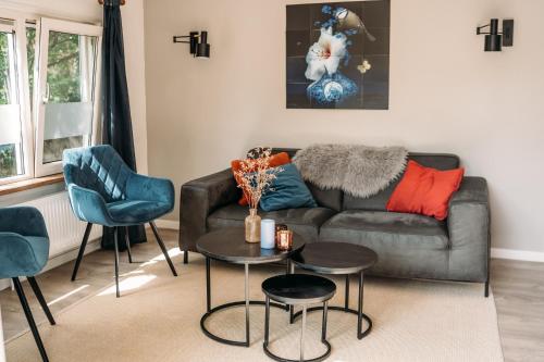 a living room with a couch and two chairs at Forrest Lodge in bosrijke omgeving de Veluwe - met terras, tuin en fietsschuurtje in Nunspeet