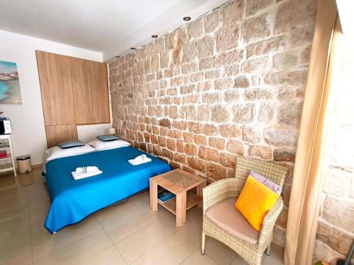 a bedroom with a blue bed and a brick wall at Studio Apartment Legcevic in Kaštela