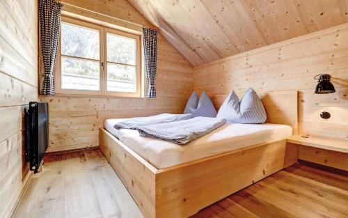 a bed in a wooden room with a window at CASALPIN Chalets in Brand