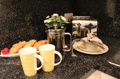 a table with two cups and a plate of pastries at The Eistedfod Penthouse - Berwyn House in Wrexham