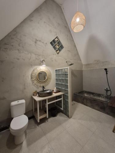 a bathroom with a toilet and a sink and a mirror at Mulyanus Hotel by Calli Rooms in Wirolegi