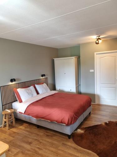 a bedroom with a large bed with a red blanket at Bed and Breakfast De Dijk in Zuid-Beijerland