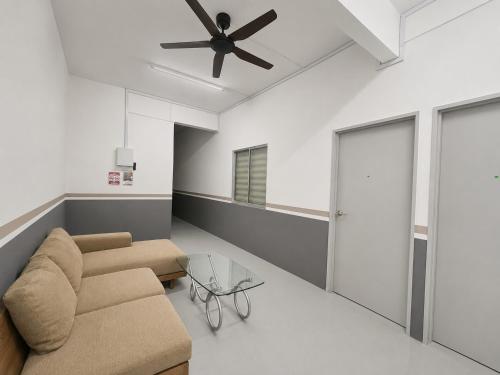 a living room with a couch and a ceiling fan at Singtown Guesthouse in Mersing