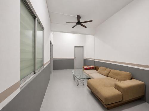 a living room with a couch and a ceiling fan at Singtown Guesthouse in Mersing