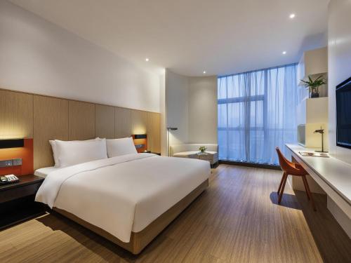 a bedroom with a large white bed and a desk at Mercure Nanjing Olympic EXPO in Nanjing