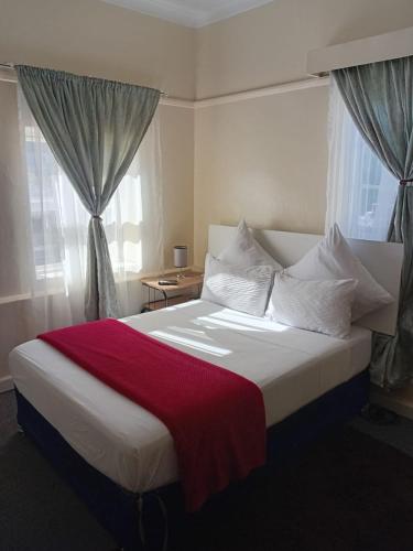 a bedroom with a large bed with a red blanket on it at Faranie Guesthouse in Oudtshoorn
