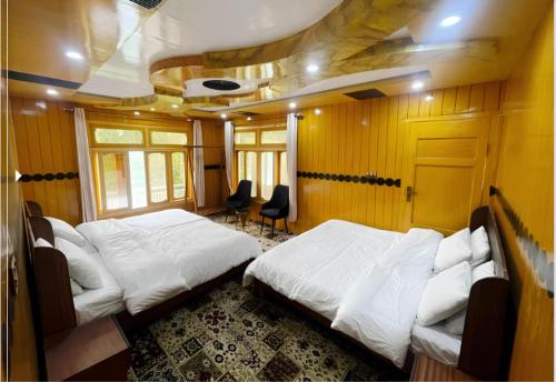 a room with two beds and two chairs in it at Alpine Resort Khaplu in Khaplu