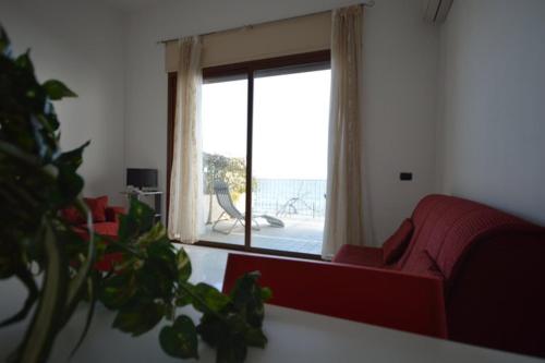 salon z czerwoną kanapą i oknem w obiekcie Riva Beach Apartment w mieście Riva Ligure