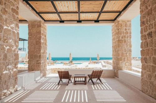 a patio with a table and chairs on the beach at Wadi Sabarah Lodge in Abu Dabbab