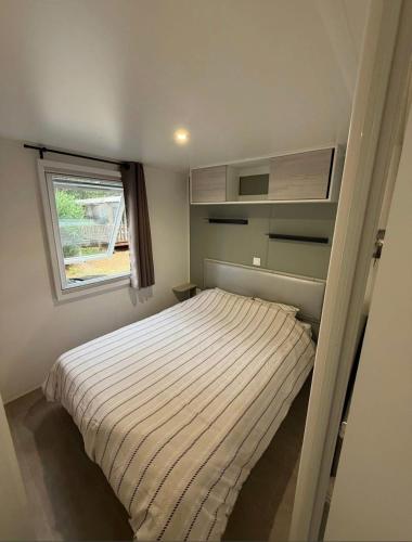 a small bedroom with a bed and a window at Mobil Home SIBLU VALRAS PLAGE in Sérignan