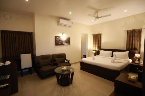 a hotel room with a bed and a chair at Aroma Ayur Heritage in Mattanūr