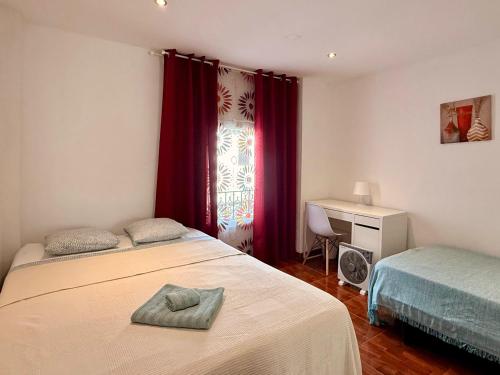 a bedroom with two beds and a window with red curtains at Apartamento "El Casco Antiguo" in Xàtiva