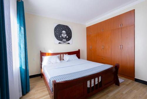 a bedroom with a bed and a wooden cabinet at SereneKey Stays in Kigo
