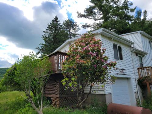 a white house with a balcony and a tree at Wine and roses farm house in Waymart