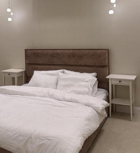 a bed with white sheets and two side tables at شاليهات أفق in Jeddah