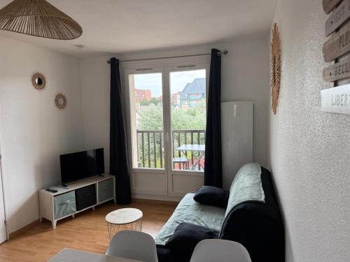 a living room with a couch and a window at T2, accès direct plage, proche thalasso in Cabourg