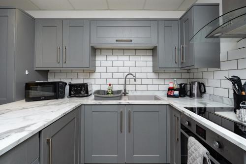 a kitchen with white cabinets and a sink at Open Mind Property - Spacious 2BR Flat City Views in Portsmouth