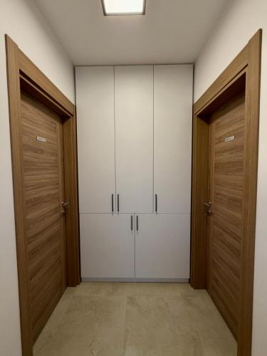 a walk in closet with white cabinets and wooden doors at Taca 1 - Airport apartman in Surčin