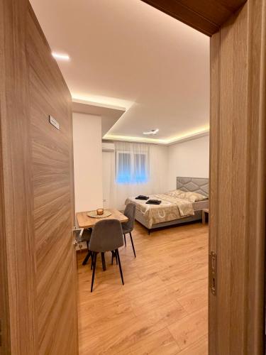 a room with a bed and a table and a room with a bedroom at Taca 1 - Airport apartman in Surčin