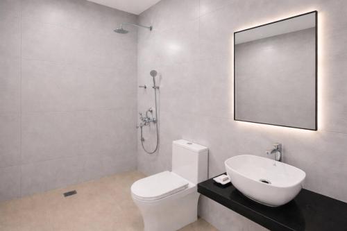 a bathroom with a toilet and a sink and a mirror at High Five Hotels Phase 2 in Assagao