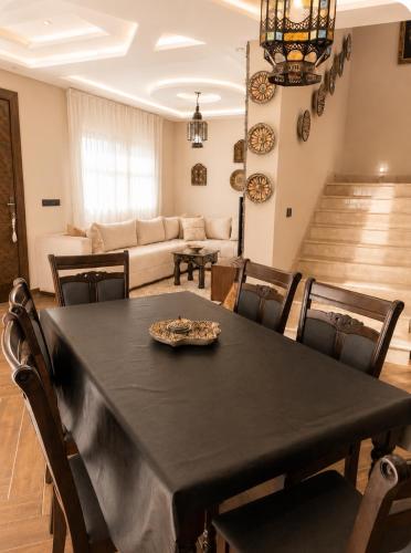 a dining room with a black table and chairs at Azra Luxe villa famille uniquement Family only in Saïdia