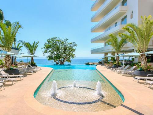a swimming pool with a fountain in front of a building at CONDO FRENTE AL MAR Hermoso con amenidades in Bucerías