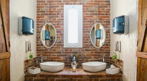 a bathroom with two sinks and mirrors on a brick wall at Casa Biba in Utique