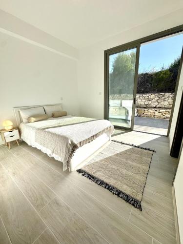 a white bedroom with a bed and a large window at Villa Tuludis in Drousha