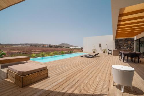 a house with a wooden deck with a swimming pool at Villa Karuna by Aura Collection in Villaverde