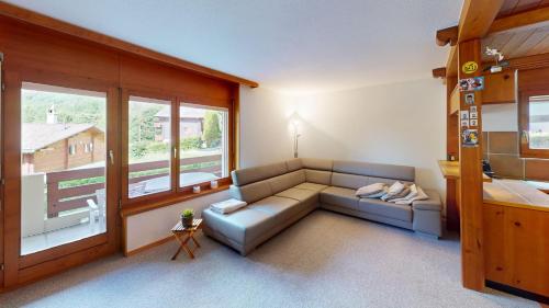 a living room with a couch and a large window at Haus Belstar A in Naters