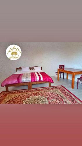 a bedroom with a bed and a table and a rug at Айкол Этно Комплекс in Tong