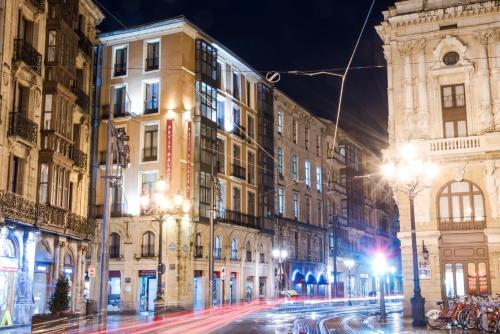 una calle de la ciudad por la noche con edificios y luces en Petit Palace Arana Bilbao, en Bilbao