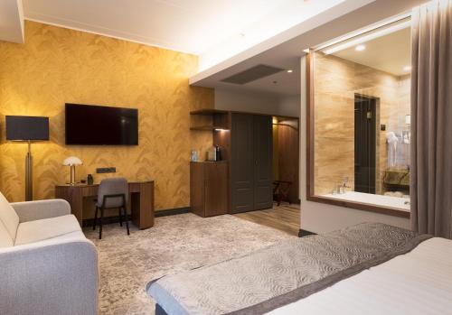 ein Hotelzimmer mit einem Bett, einem Schreibtisch und einem TV in der Unterkunft V Spa & Conference Hotel in Tartu
