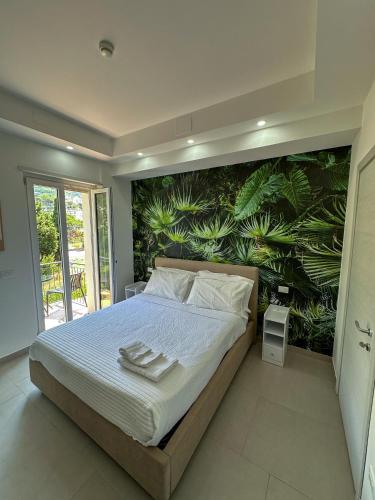 a bedroom with a large bed with a tropical wall at Beach House - Affittacamere Paola in Paola