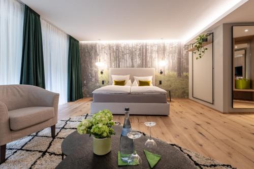 a bedroom with a bed and a chair and a table at Sackmann Design Genuss & SPA Resort in Baiersbronn
