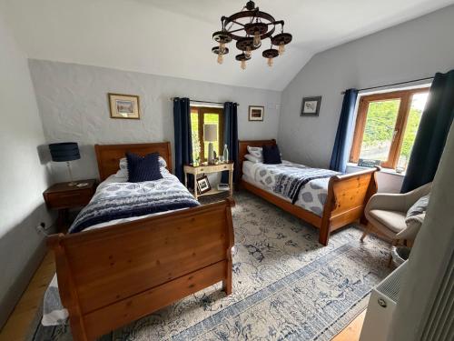 a bedroom with two beds and a chair and a chandelier at Salmon Weir Lodge in Cong