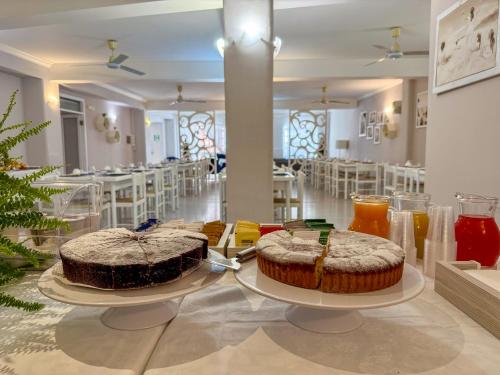 two cakes on plates on a table in a room at Hotel Odissea in Canneto