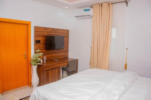 a bedroom with a bed and a desk with a tv at Five Star Meekness Hotel LTD in Oviri