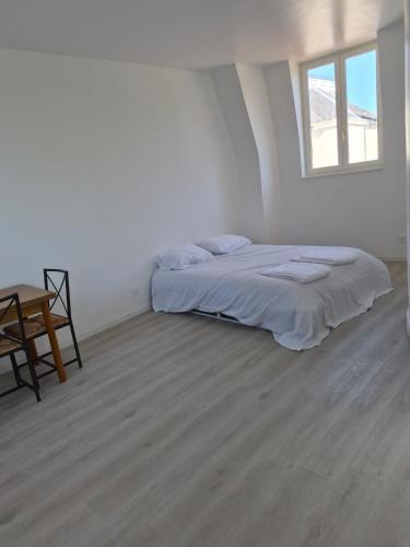 a white room with a bed and a table at Maison chaleureuse avec tous confort in Elbeuf