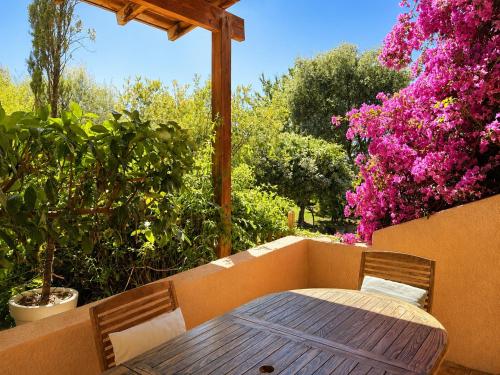 a wooden table and chairs on a patio with flowers at Résidence Guddelmoni, Piscines chauffées in Propriano