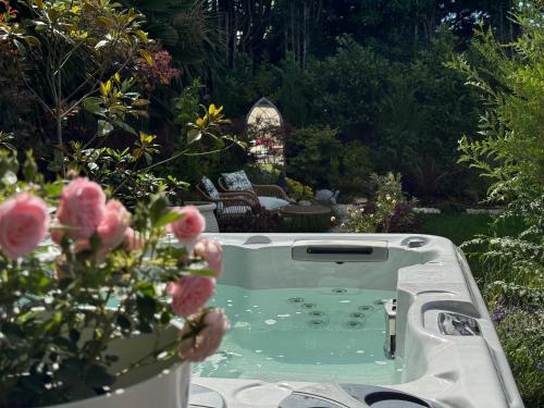 a bath tub in a garden with pink roses at Balancyoga Guesthouse in Ash