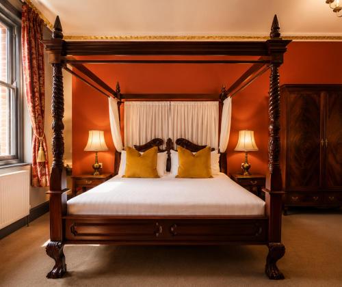 a bedroom with a canopy bed with yellow pillows at The Godwins in Hereford
