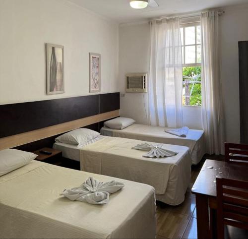 a hotel room with three beds and a window at Hotel Natal in Santos