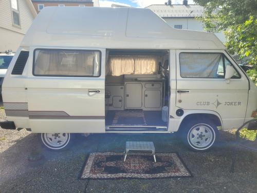 a white van parked in a parking lot with the door open at Sleep inside a classic Volkswagen Westfalia or our legendary Mercedes Düdo overland cabin in central Svolvær Close to public showers and toilets NO PARKING in Svolvær