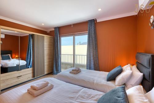 two beds in a room with a large window at Central Malta Gem - 3BR Apartment with Balconies in Mosta