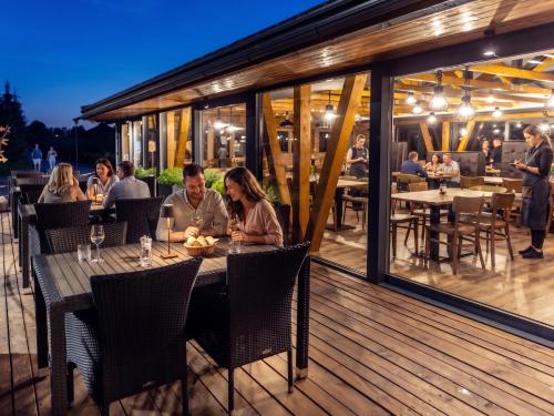a group of people sitting at a table on a deck at Resort Drevenice Terchova in Terchová