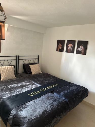 a bed in a room with pictures on the wall at Garden Suite Vila Girasoles in Cálig