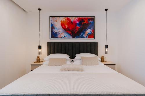 a bedroom with a large white bed with a heart painting at Matej's rooms in Korčula